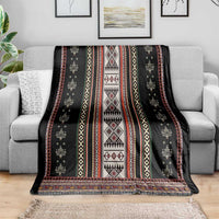 Black folk blanket draped over couch with red, white, and yellow geometric panel design