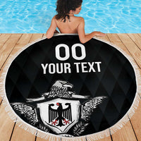 Black round beach blanket with fringe edge featuring '00 YOUR TEXT' and eagle crest design