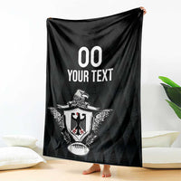 Black rugby blanket with eagle crest and '00 YOUR TEXT' print, held upright