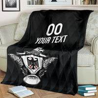 Black rugby blanket with eagle crest and '00 YOUR TEXT' print, draped over loveseat