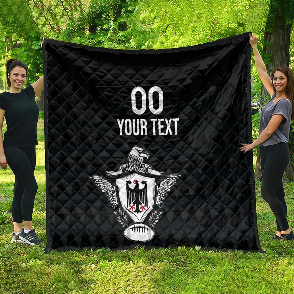 Black quilted rugby throw blanket spread on grass with eagle crest and “YOUR TEXT”