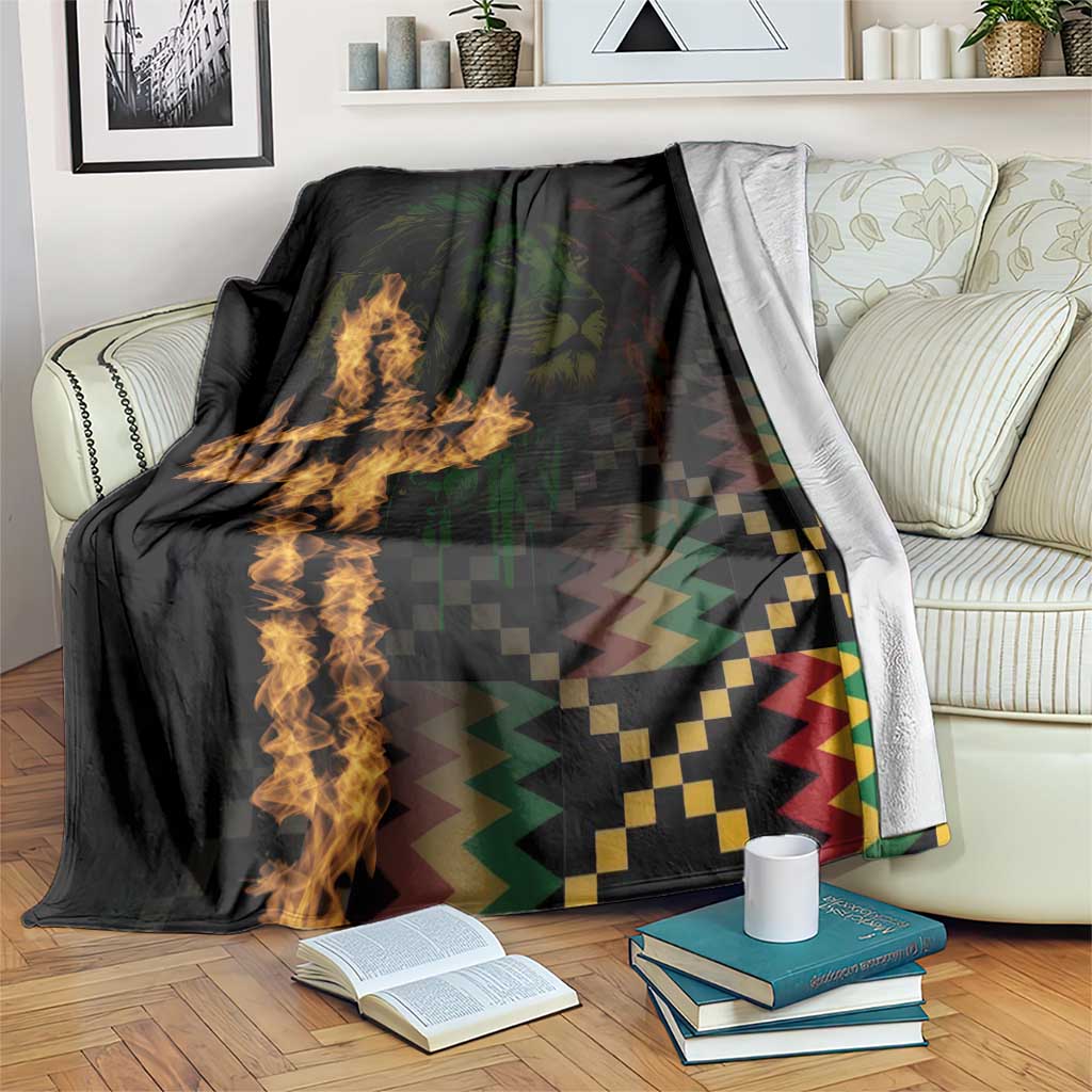Black printed blanket draped on sofa, showing lion portrait and cross flame with zigzag pattern