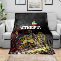 Meskel Ethiopia blanket on couch, black with gold lion, ETHIOPIA lettering, and distressed print
