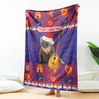 Red and blue plaid Christmas blanket with koala in Santa hat and guitar, draped on couch