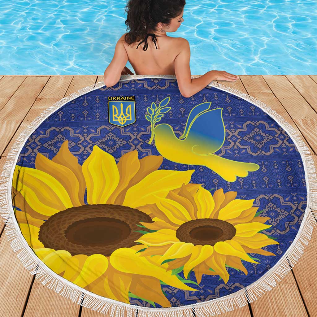 Round beach blanket featuring blue folk pattern, yellow sunflowers, and dove emblem, white fringe