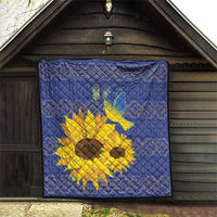Blue quilt hanging on a wall with yellow sunflowers and dove emblem.