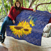 Blue quilt draped on a couch outdoors, featuring yellow sunflower and dove motif.