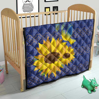 Blue quilt in a wooden crib with yellow sunflower and dove folk motif.