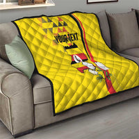 Yellow personalized quilt on gray sofa with Uganda emblem, flowers, and black edge binding