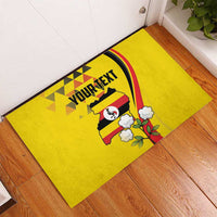 Yellow rubber doormat laid on wooden floor, YOUR TEXT banner with Uganda map and flowers