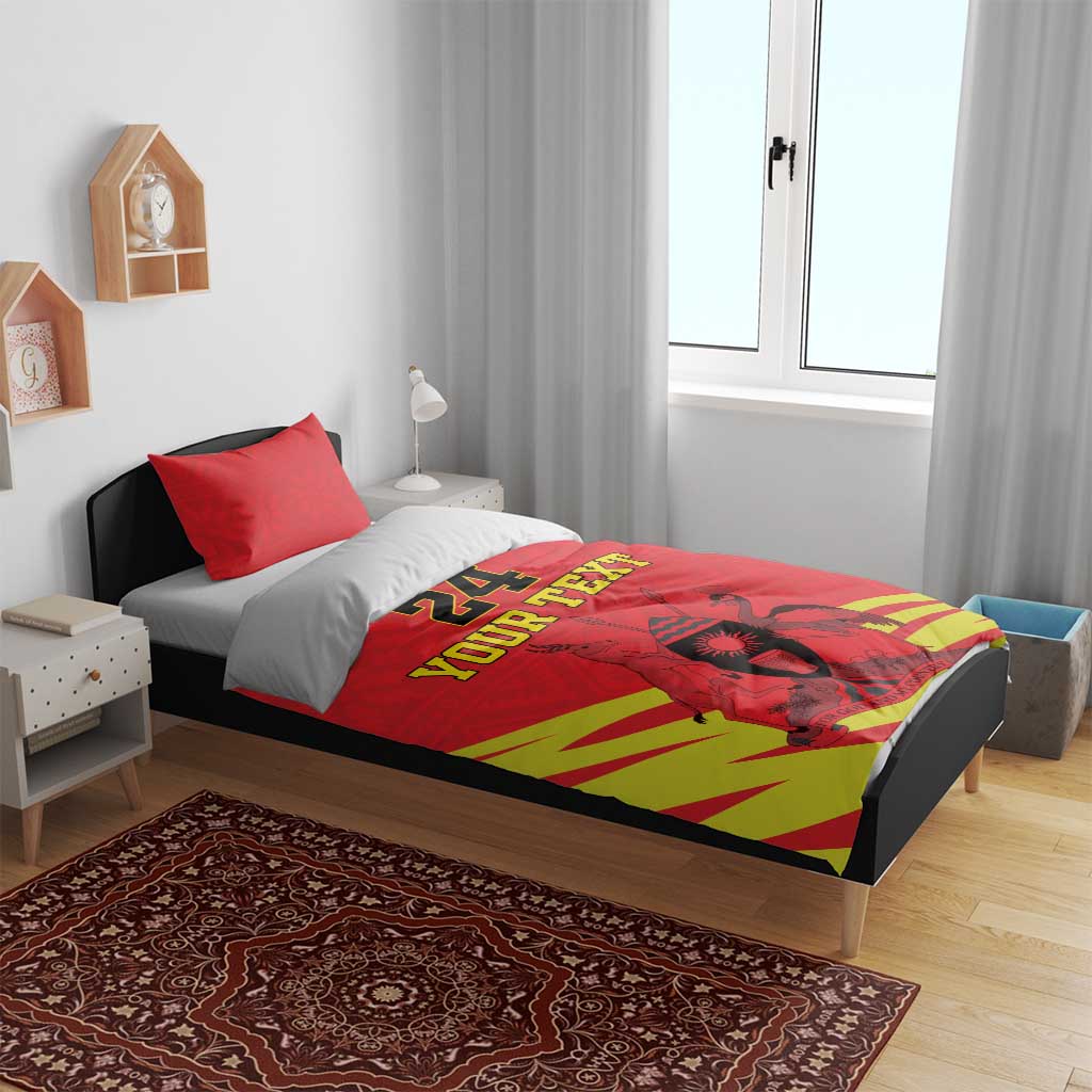 Red duvet with “YOUR TEXT” and kente striped design across the bed surface