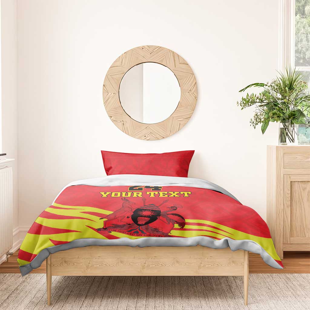 Red and yellow duvet with kente stripes and Coat of Arms, styled on a bed with gray sheets