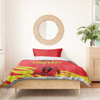 Red and yellow duvet with kente stripes and Coat of Arms, styled on a bed with gray sheets