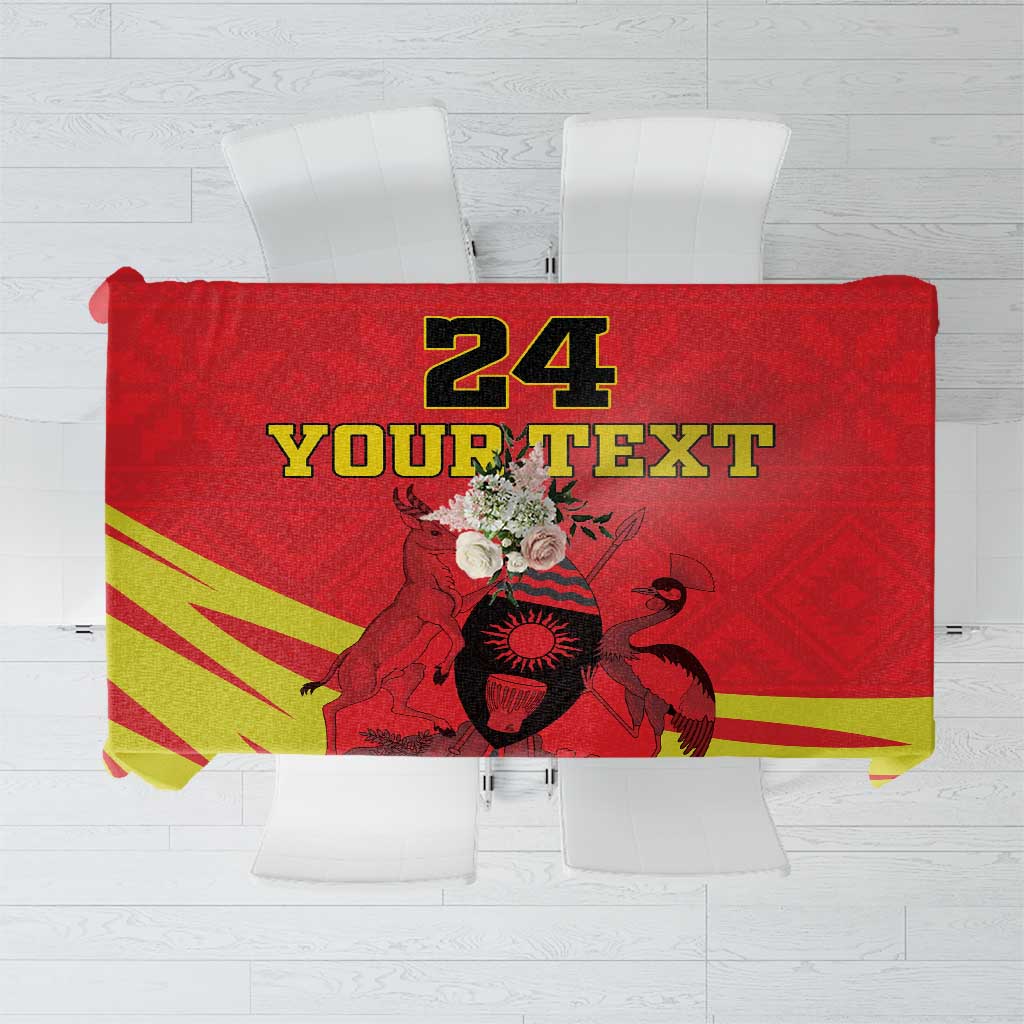 Red tablecloth with Uganda crest, yellow-green Kente-style pattern and custom text