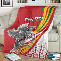 Red personalized throw blanket on armchair, crest graphic with rainbow swoosh and 'YOUR TEXT'