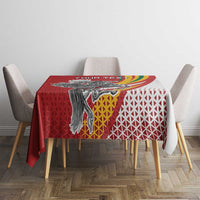 Red square tablecloth with Vytis emblem, white lattice pattern, and rainbow swoosh border.