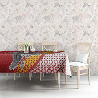 Red tablecloth on dining table featuring Vytis emblem, white geometric lattice, rainbow swoosh.