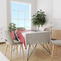 Red and white tablecloth on dining table with folded corners and crest design