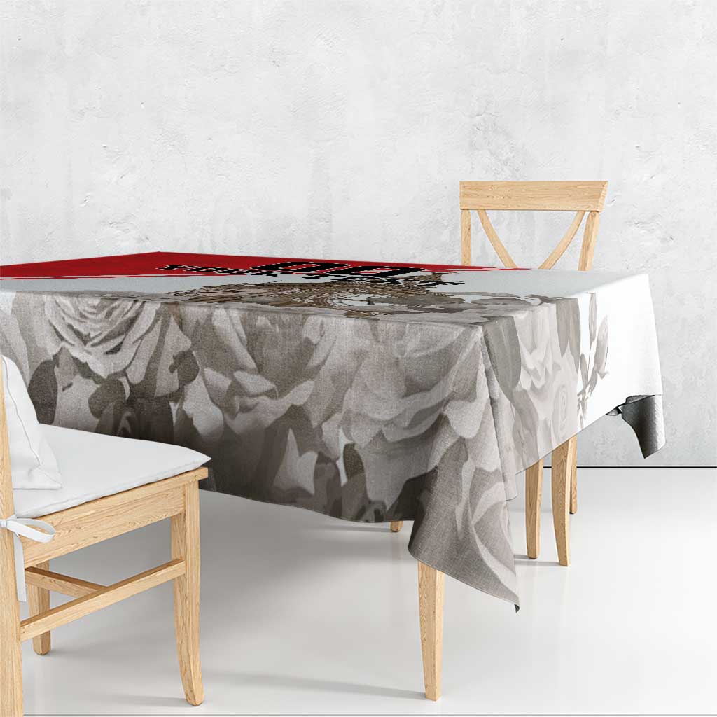 White tablecloth with gray rose and leaf pattern and red border stripe, hanging over table