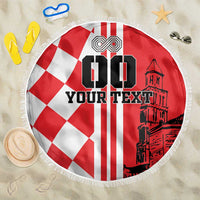 Round red and white beach blanket with checkered design, black town graphic, fringe edge