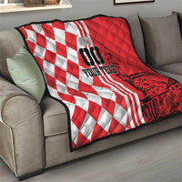 Red and white checkerboard quilt with black city graphic, laid across a sofa