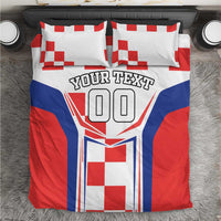 Bedding set in red, white and blue with two pillows, checker pattern, crest and 'YOUR TEXT'.