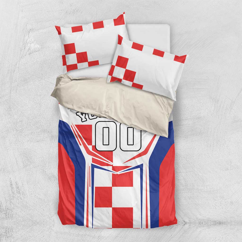 Bedding set on light surface with two pillows; red, white and blue crest and 'YOUR TEXT'.