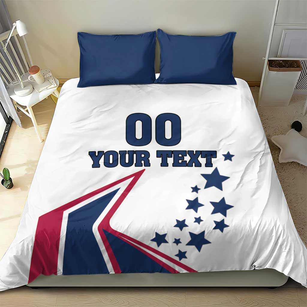 White bedding set with two navy pillowcases; comforter shows '00 YOUR TEXT' and flag graphic