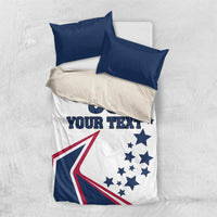 White bedding set with two navy pillowcases; comforter with stars, flag graphic, and 'YOUR TEXT'