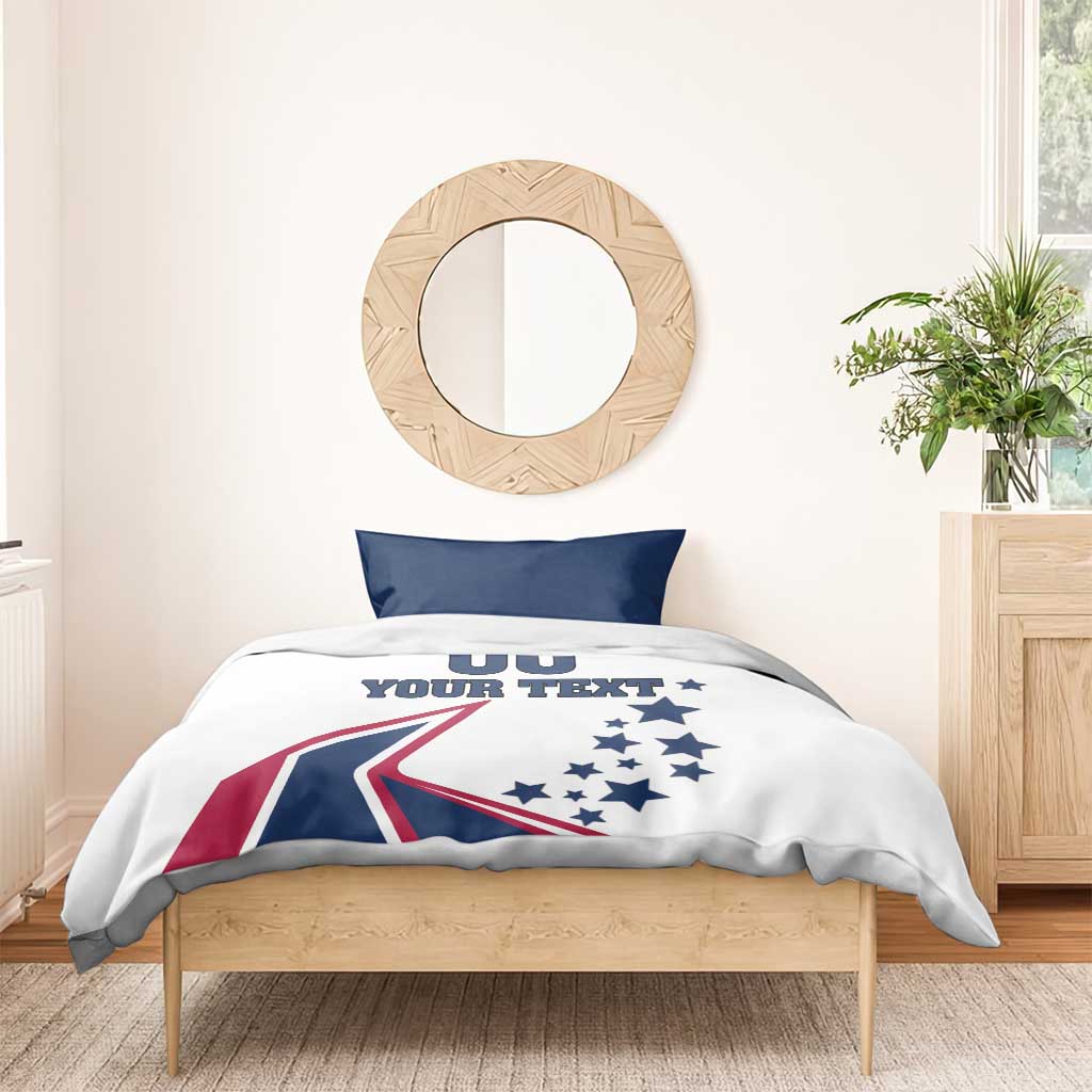 White bedding set with two navy pillowcases; comforter shows stars, flag graphic, and 'YOUR TEXT'
