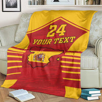 Spain-themed sports blanket on a living room sofa, red and yellow with coat of arms map and 24