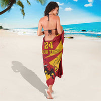 Red and yellow sarong with “24 YOUR TEXT” and bull graphic, side-tied, back view