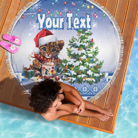 Round blue beach blanket with leopard kitten in Santa hat, decorated Christmas tree