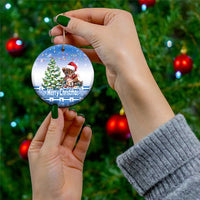 Blue round ceramic Christmas ornament held in hand, cat Santa hat with “Merry Christmas”