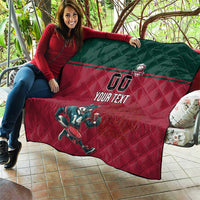 Custom rugby quilt held on couch: dark green top, red quilted surface, wolf mascot, "YOUR TEXT"