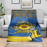 Blue and yellow Ukrainian folk sunflower blanket on couch with “SLAVA UKRAINE!”