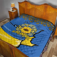 Quilt laid on a wooden bed: blue fabric, yellow band, folk trim, dove and sunflower
