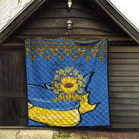 Blue quilt hanging on wall with folk border, sunflower peace sign, and dove graphic