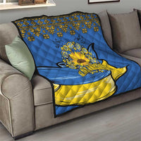 Blue quilt draped over sofa with folk trim, yellow hem, sunflower peace sign and dove