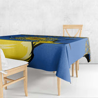 Blue tablecloth draped over wooden dining table with yellow trident and sunflower design