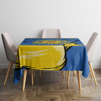 Blue tablecloth with yellow trident and sunflower folk pattern covering dining table center