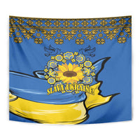 Blue wall tapestry close-up with yellow sunflower wreath, folk top border, "Slava Ukraine!" text