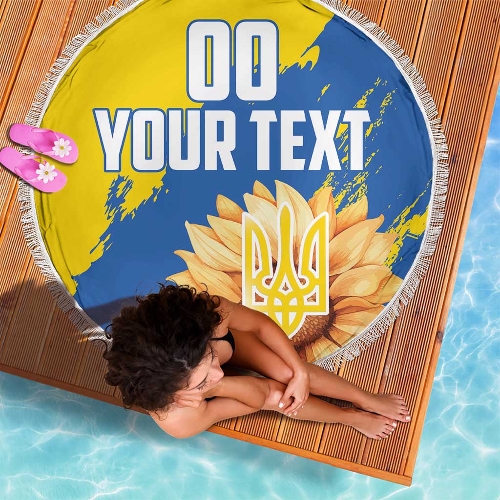 Round beach blanket with fringed edge, yellow/blue sunflower trident emblem graphic