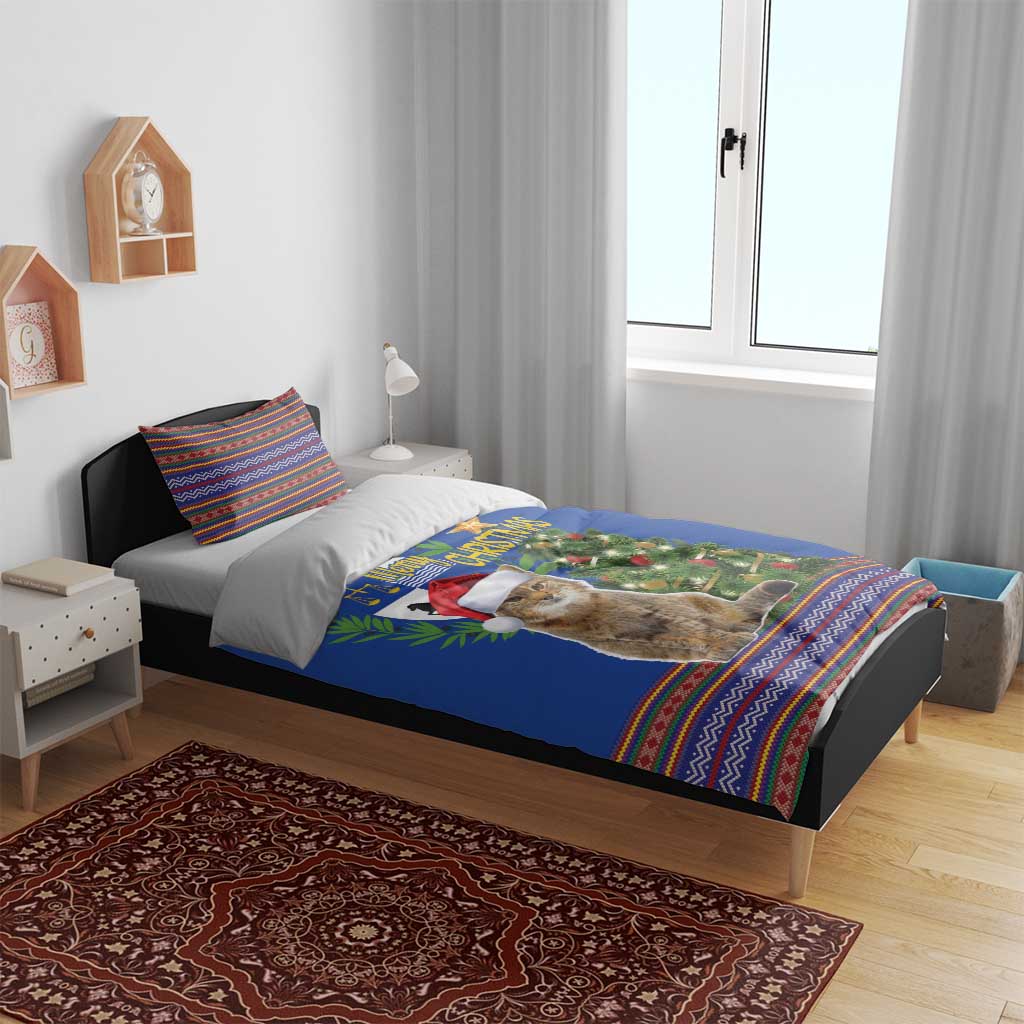Blue Christmas bedding set on bed featuring cat with Santa hat, tree scene and folk borders