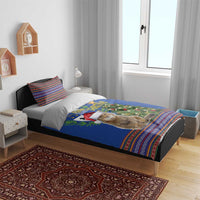 Blue Christmas bedding set on bed featuring cat with Santa hat, tree scene and folk borders