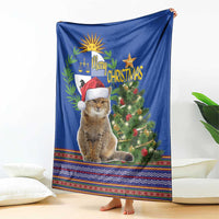Blue Christmas blanket draped with cat in red hat, evergreen tree, and colorful geometric border