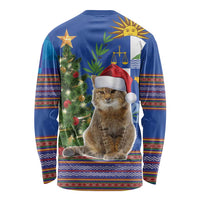 Blue long-sleeve Christmas shirt with seated cat wearing Santa hat, tree and folk trim
