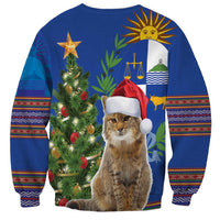 Blue unisex Christmas sweatshirt with cat in Santa hat, tree lights, and folk patterned sleeves
