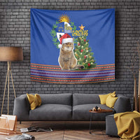 Blue Christmas tapestry with sitting cat wearing Santa hat and small tree
