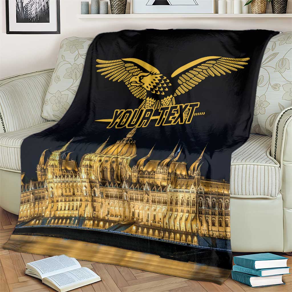 Black blanket with gold bird emblem and Budapest skyline on a sofa